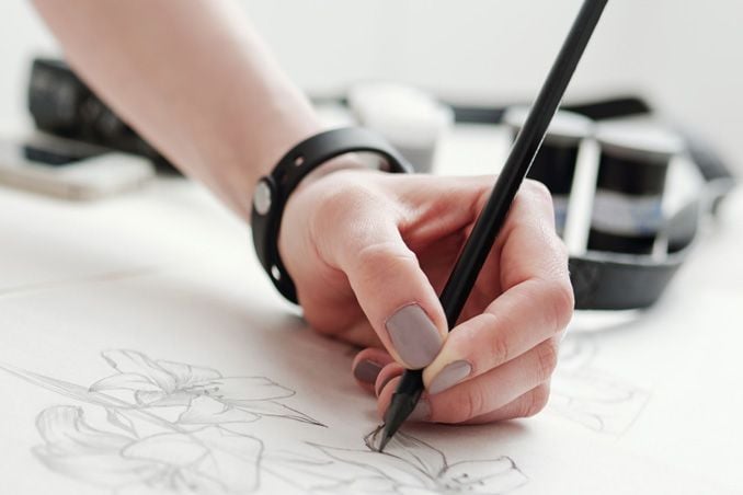 Design teams hand sketching character illustration with digital pen on paper at creative design workspace desk