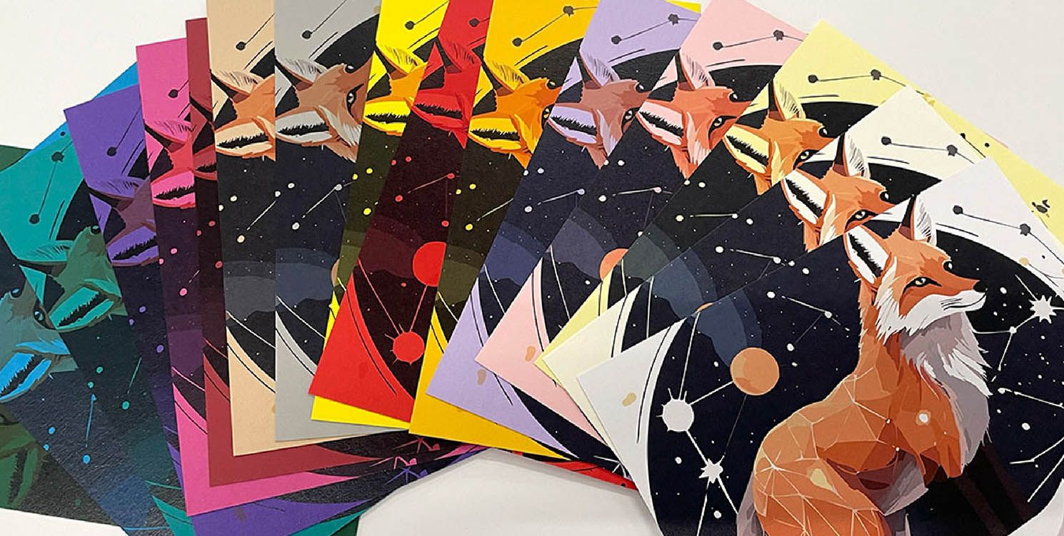 A fan of printed cards on Colorplan paper shades showing a stylised fox illustration against starry night backgrounds in multiple colours.