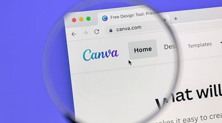 Canva website homepage viewed through magnifying glass showing online graphic design platform