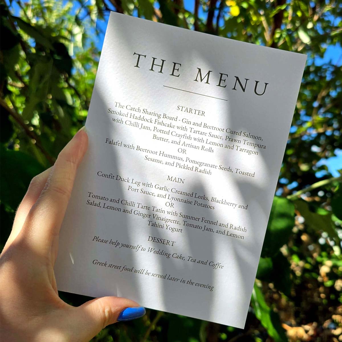 Tintoretto Gesso 5x7 wedding menu with elegant minimalist typography, printed on textured off-white card and photographed outdoors in natural light.